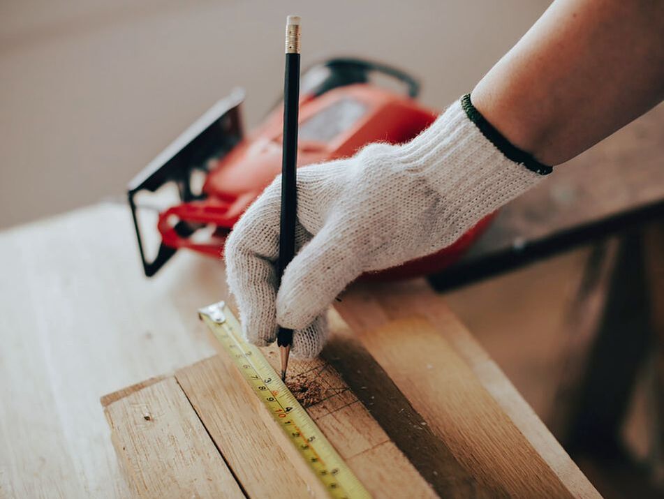 Carpenter measuring and making pencil marks on wood